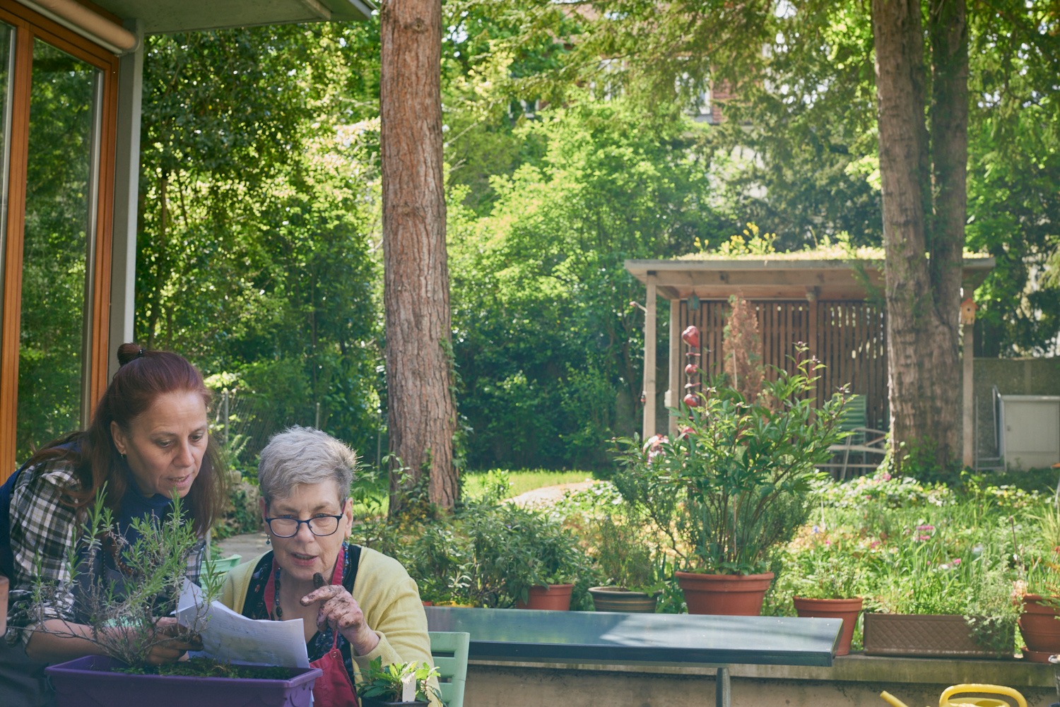 Bewohnerin beim Lesen auf einer Terrasse im Grünen